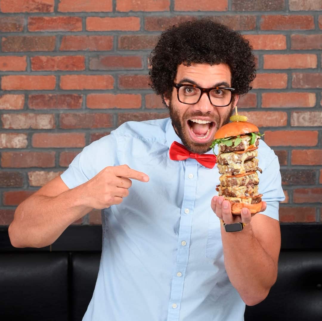 Blake holding a burger looking enthusiastic